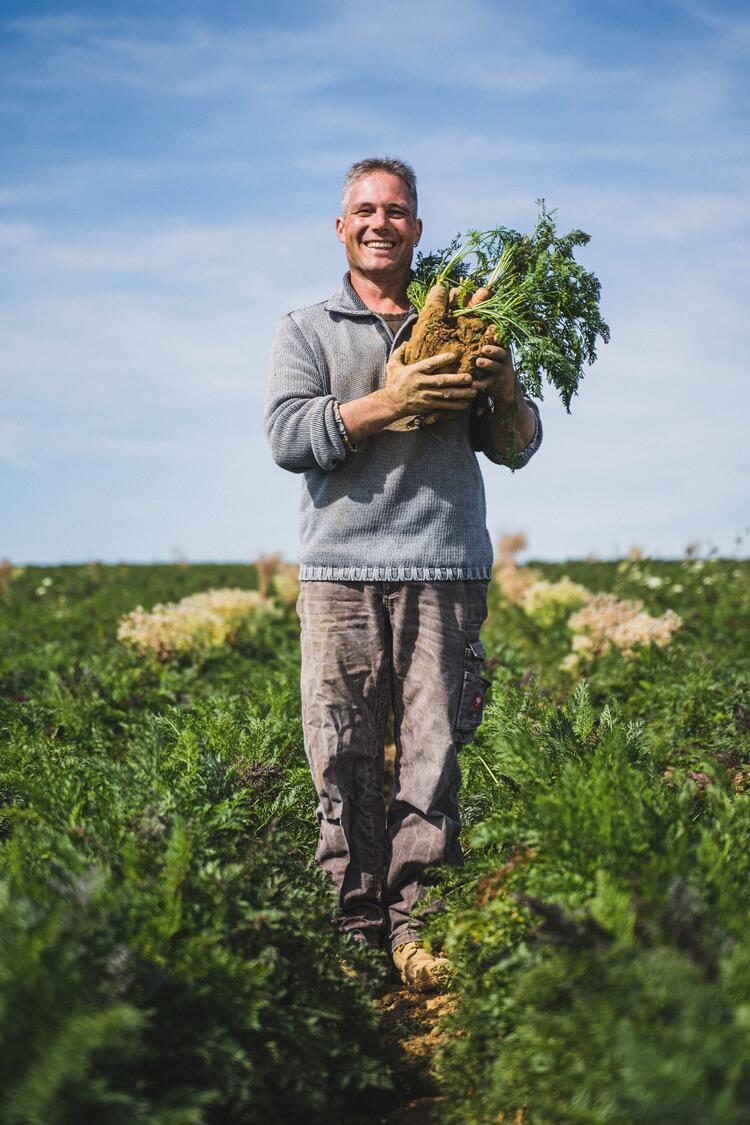 Thomas Schneider mit Möhren im Arm auf einem Feld